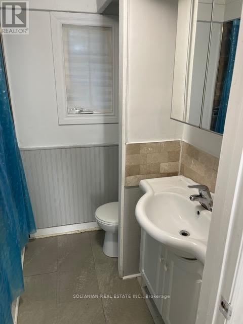 A bathroom with a toilet, sink, and mirror.
