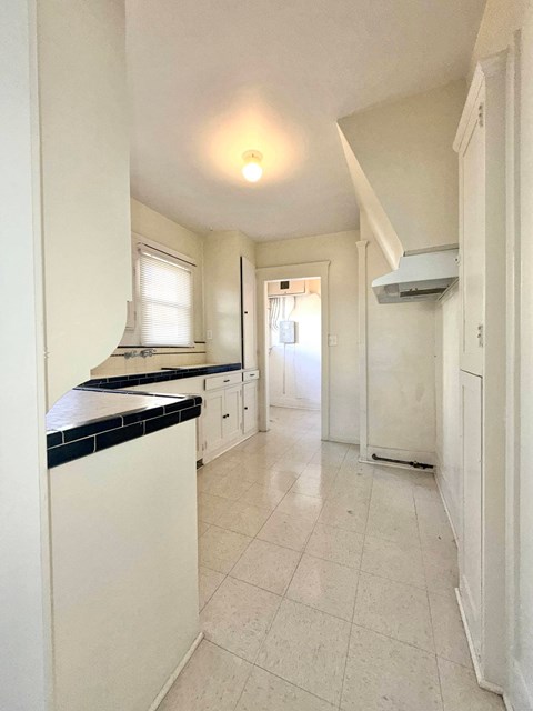 A kitchen with white cabinets and a black counter top.