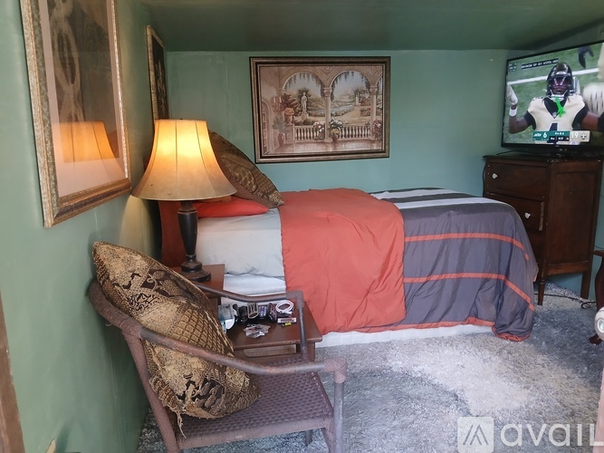 A bedroom with a bed, a chair, a lamp, and a television.
