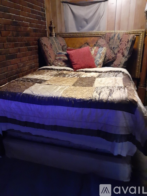 A bed with a striped comforter and a pillow with a red pillowcase.