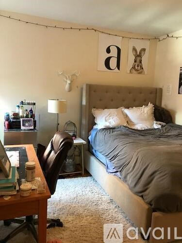 A bedroom with a bed, desk, chair, and a bunny decoration on the wall.