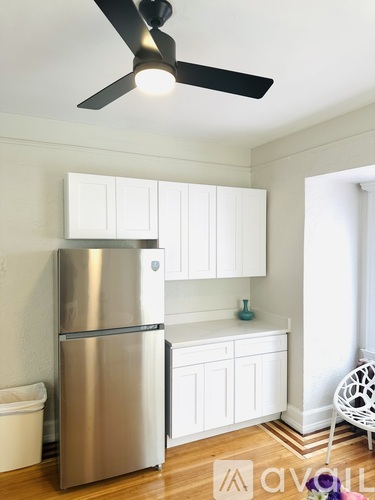 A kitchen with a stainless steel refrigerator and white cabinets.