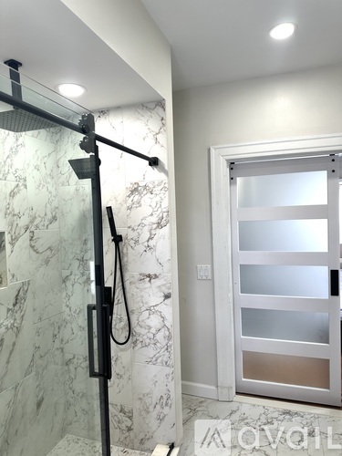 A white door with a glass panel is in a bathroom with a marble wall.