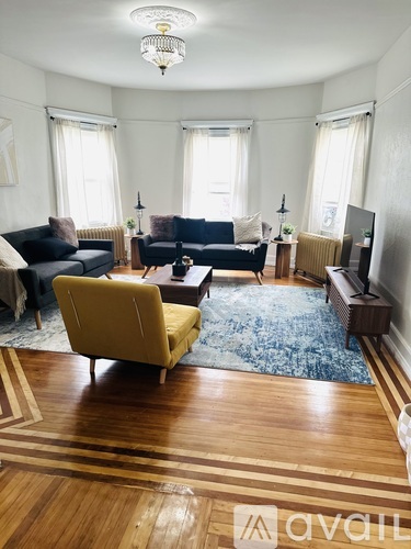 A living room with a yellow chair and a blue rug.