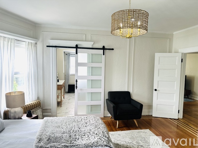 A bedroom with a bed, chair, and sliding door.