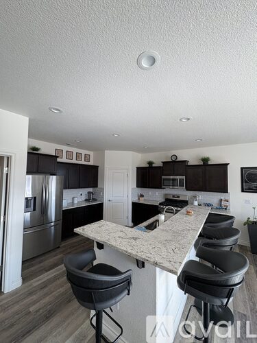 A kitchen with a marble countertop and black barstools.