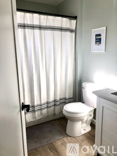 A white toilet in a bathroom with a white shower curtain.