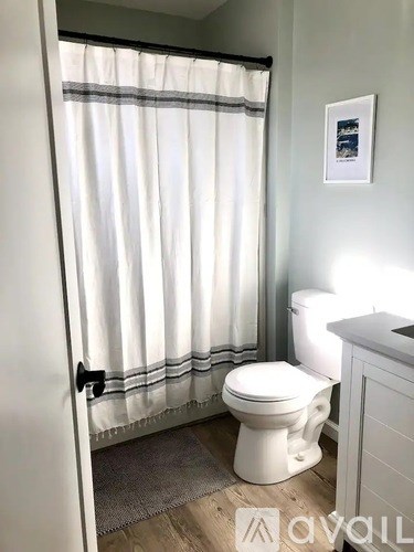 A white toilet in a bathroom with a white shower curtain.
