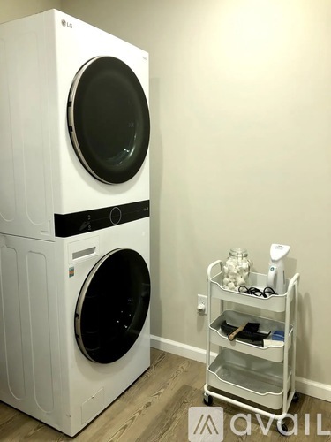A white LG front load washing machine with a black door sits next to a white wall.