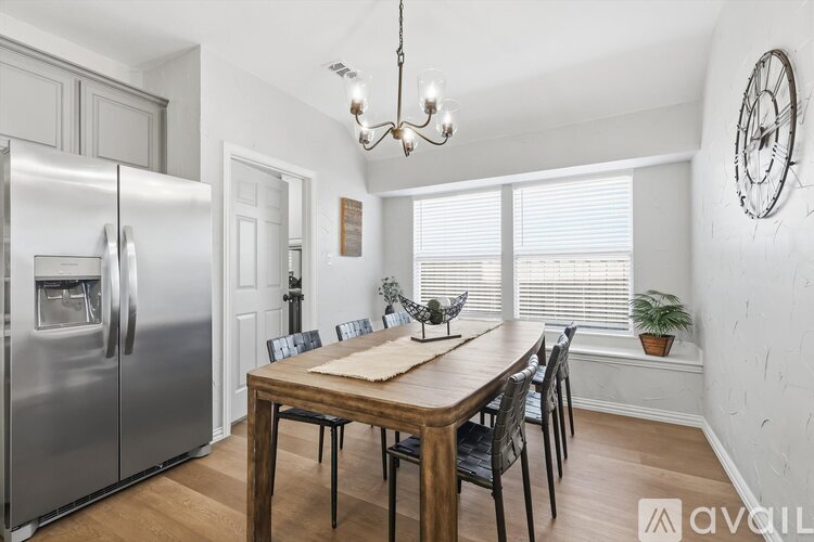 A kitchen with a wooden table and chairs, a refrigerator, and a chandelier.