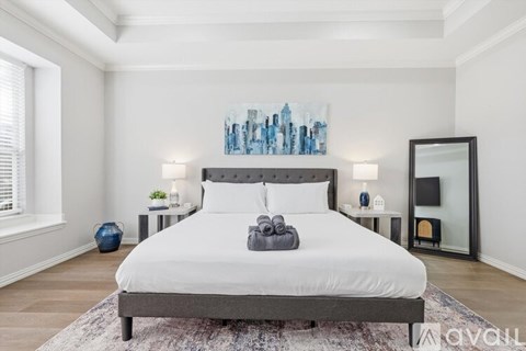 A bedroom with a large bed and a cityscape painting on the wall.