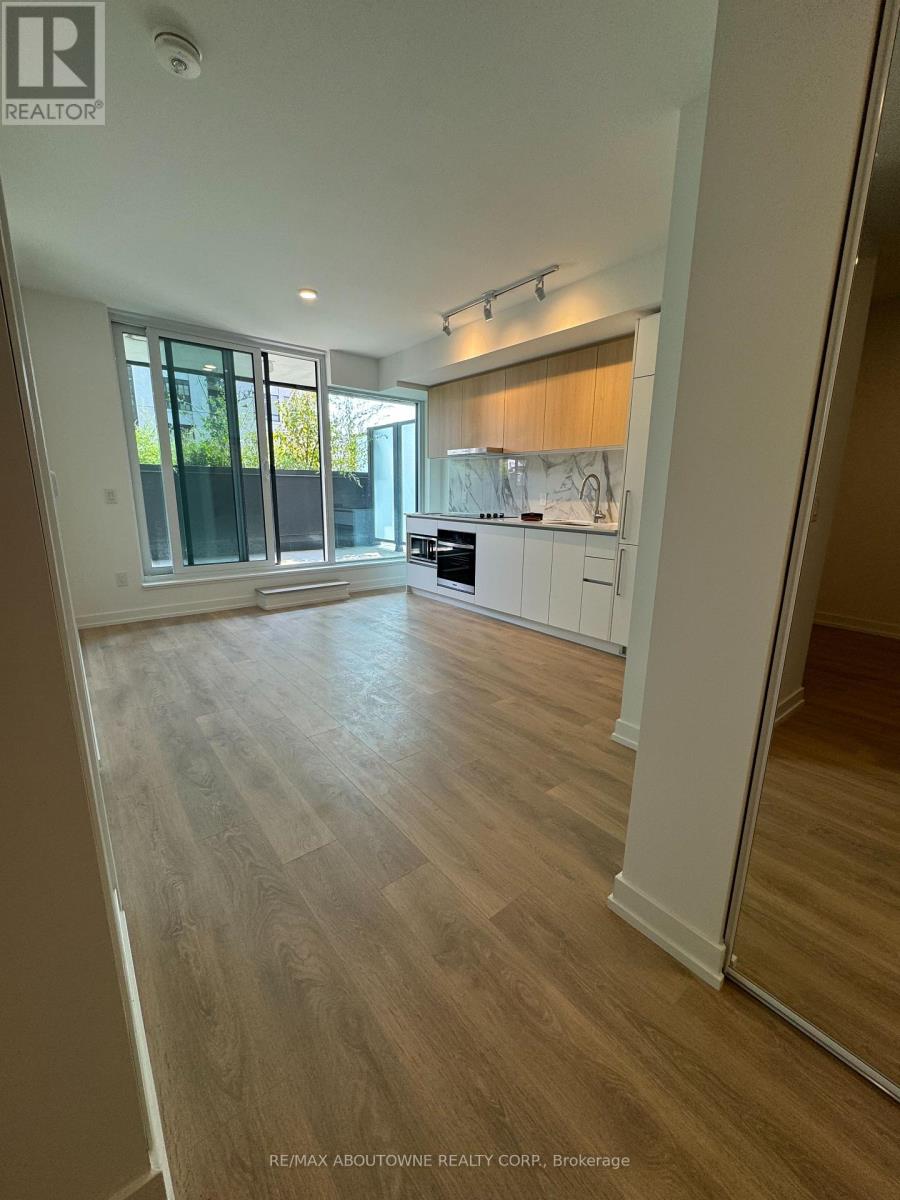 A spacious kitchen with wooden flooring and white appliances.