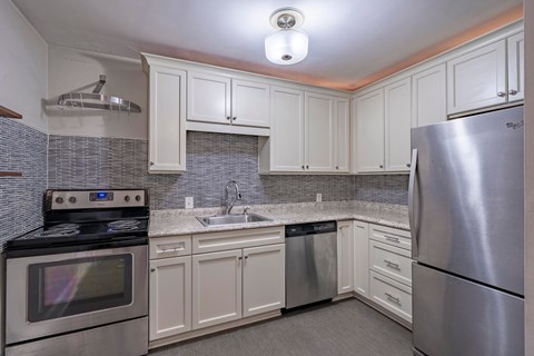 A kitchen with white cabinets and a stainless steel refrigerator.