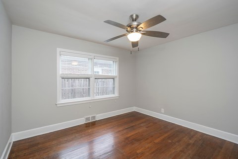 A room with a ceiling fan and a window with blinds.