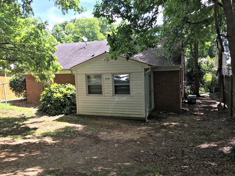 A small house with a brown roof is surrounded by trees.