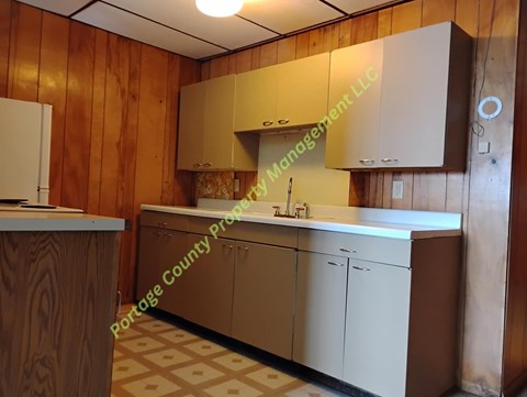 A kitchen with wooden walls and a white refrigerator.