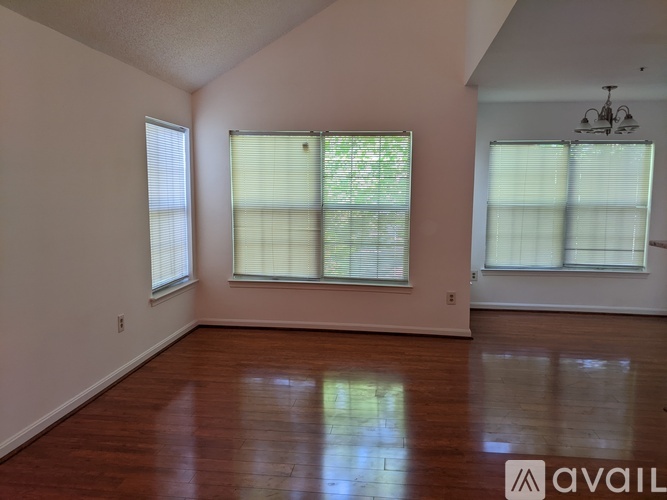 A room with wooden floors and two windows with blinds.