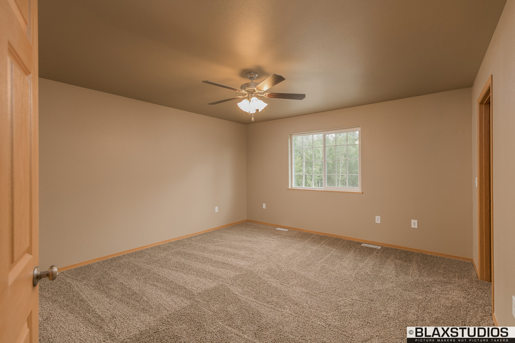 A room with a ceiling fan and carpeted floor.