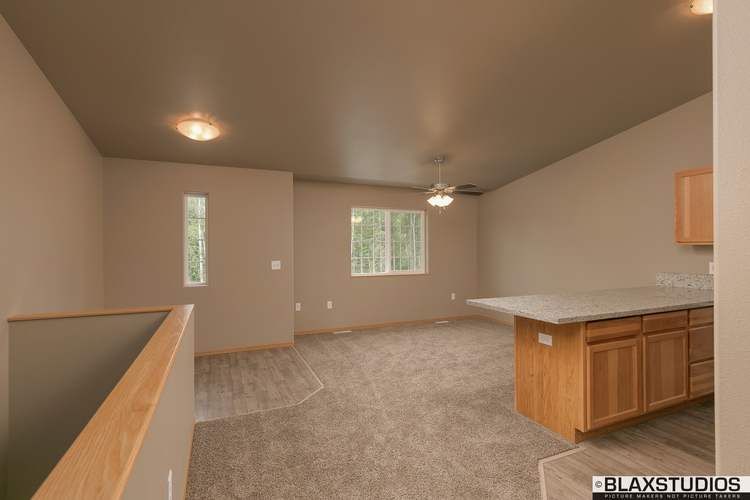 A spacious room with a carpeted floor and a ceiling fan.