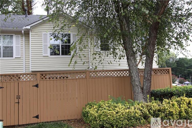 A house with a brown fence and a tree in front.