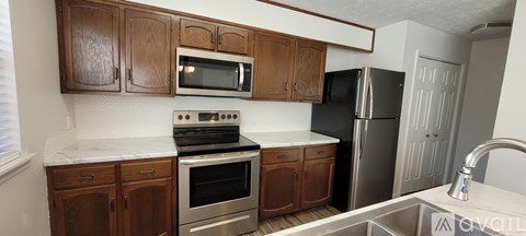 A kitchen with wooden cabinets and a black refrigerator.