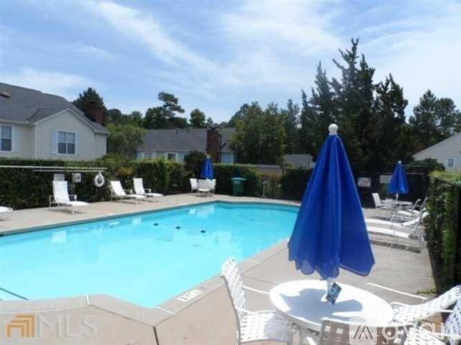 A blue umbrella is on a table next to a pool.