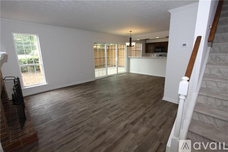 A spacious room with wooden flooring and a staircase on the right side.