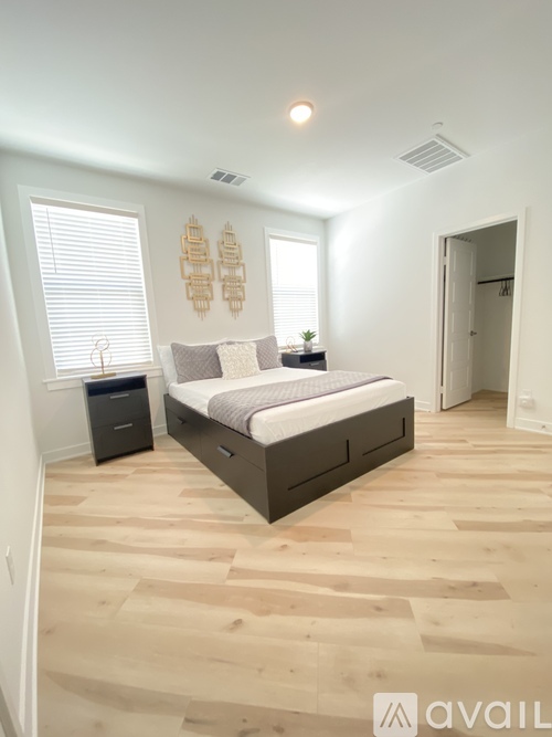 A bedroom with a bed, nightstand, and a wall hanging.
