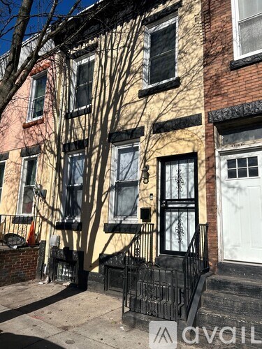 A black iron fence in front of a yellow house.