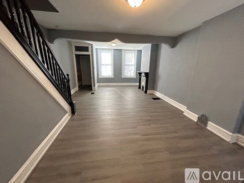 A spacious hallway with wooden floors and a staircase on the left.
