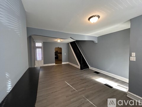 A spacious room with wooden flooring and a skylight.