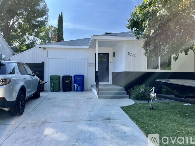 A white house with a garage and a car parked in front.