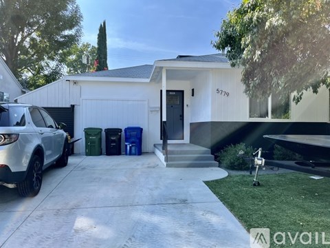 A white house with a garage and a car parked in front.