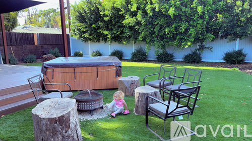 A little girl sits on the grass next to a hot tub.