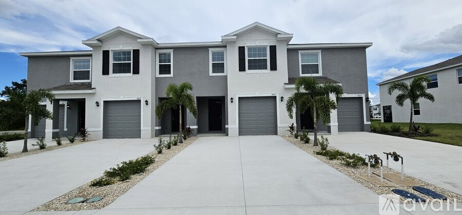 A large, modern house with a grey and white exterior and a driveway in front.