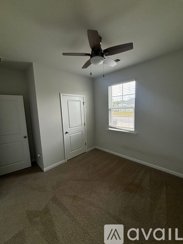 A room with a ceiling fan and a window with blinds.