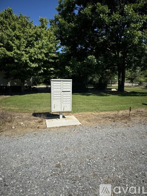 A sign in a field with trees in the background.
