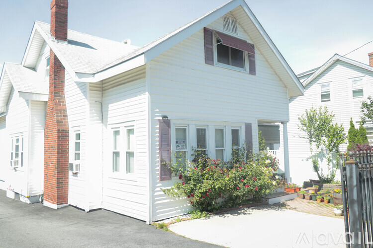 A white house with a red brick chimney and a window with a red awning.
