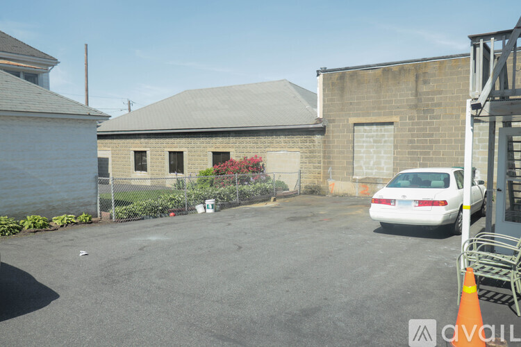 A white car is parked in a lot with a building in the background.