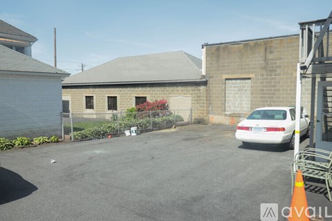 A white car is parked in a lot with a building in the background.