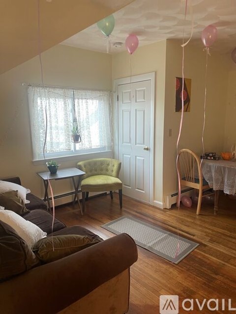 A living room with a couch, chair, and table with balloons.