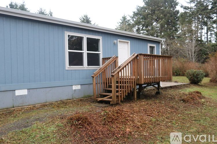 A blue house with a wooden deck and a white door.