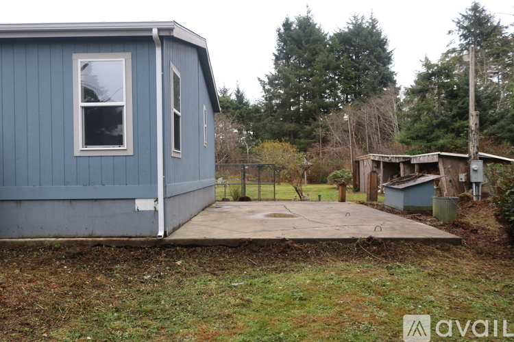 A blue house with a white window and a fence in the yard.