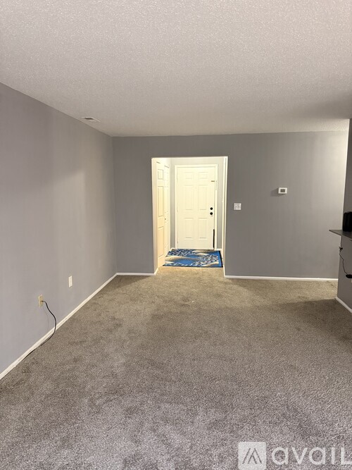 A room with a carpeted floor and a door in the background.