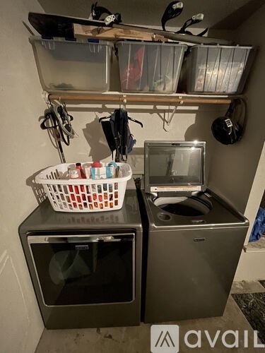A kitchen with a basket full of cleaning supplies on top of a microwave and a toaster oven.