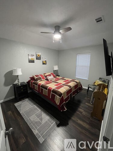 A bedroom with a bed, chair, and a ceiling fan.