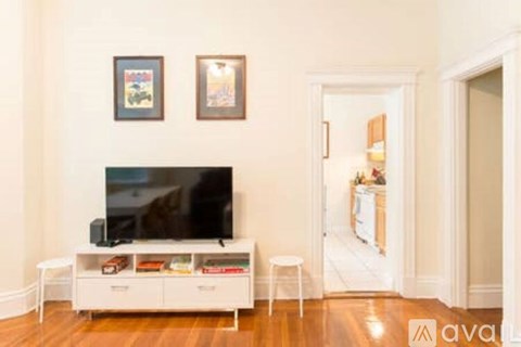 A white TV stand with a black TV on it and two framed pictures on the wall.