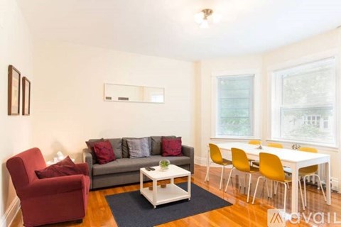 A living room with a red chair, grey couch, and a white coffee table.