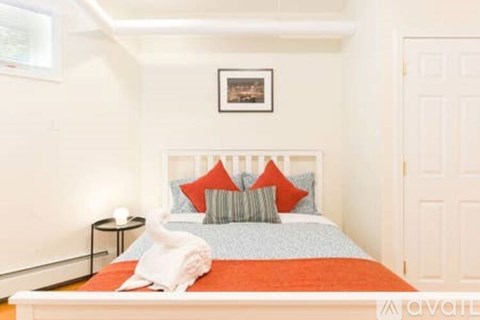 A bedroom with a bed, pillows, and a picture on the wall.