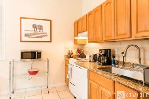 A kitchen with wooden cabinets and a fridge on the side.